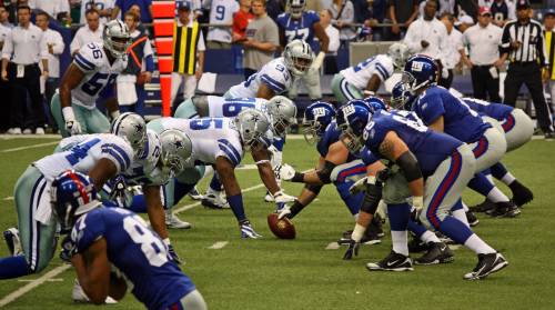 The Dallas Cowboys and the New York Giants playing a NFL game, where the Giant are about to snap the football